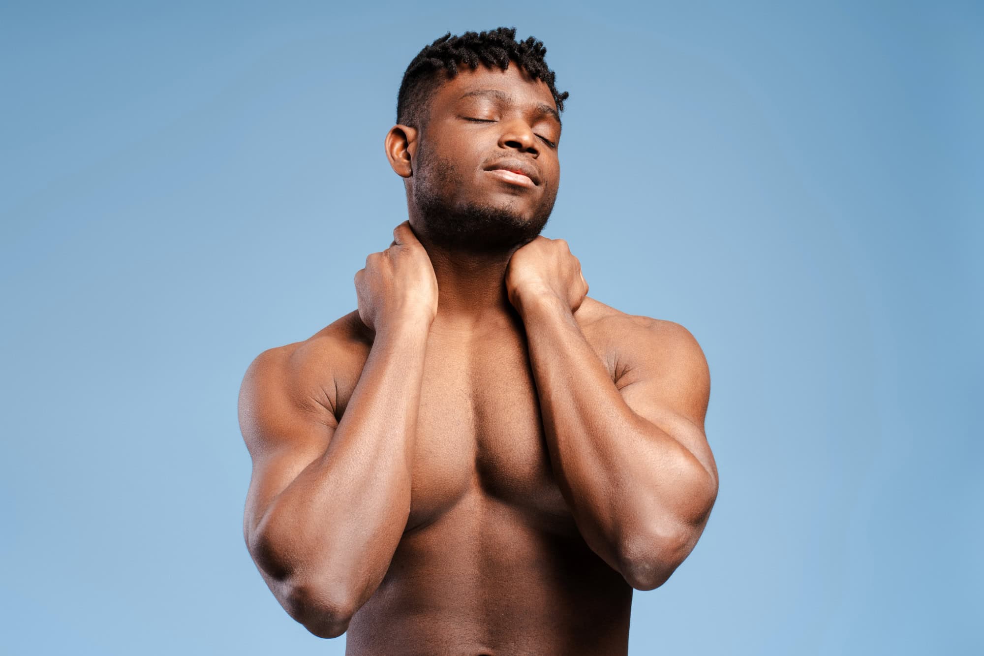 Relaxed shirtless man holding neck with eyes closed, feeling relief from neck pain