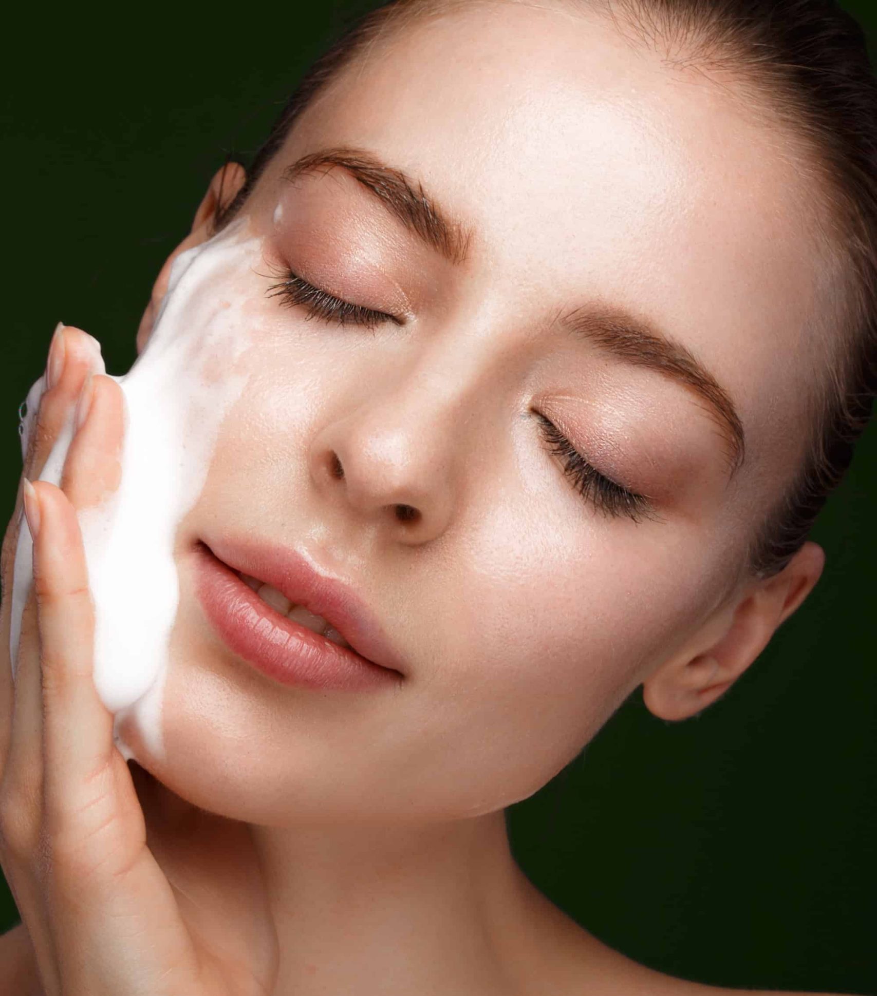 Close-up of woman gently cleansing her face with a foaming facial cleanser