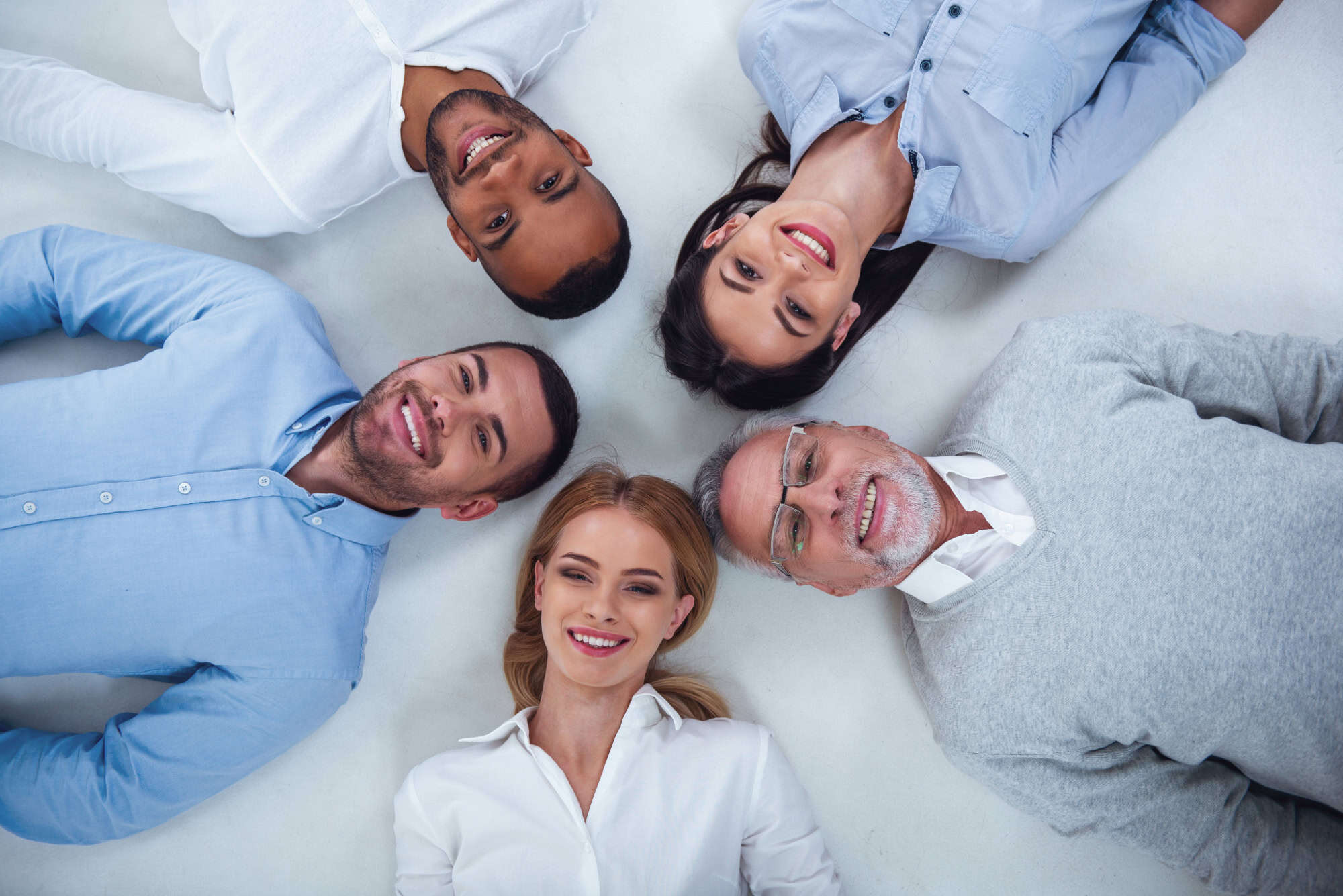 Smiling diverse group of people lying in a circle, representing all ages and backgrounds