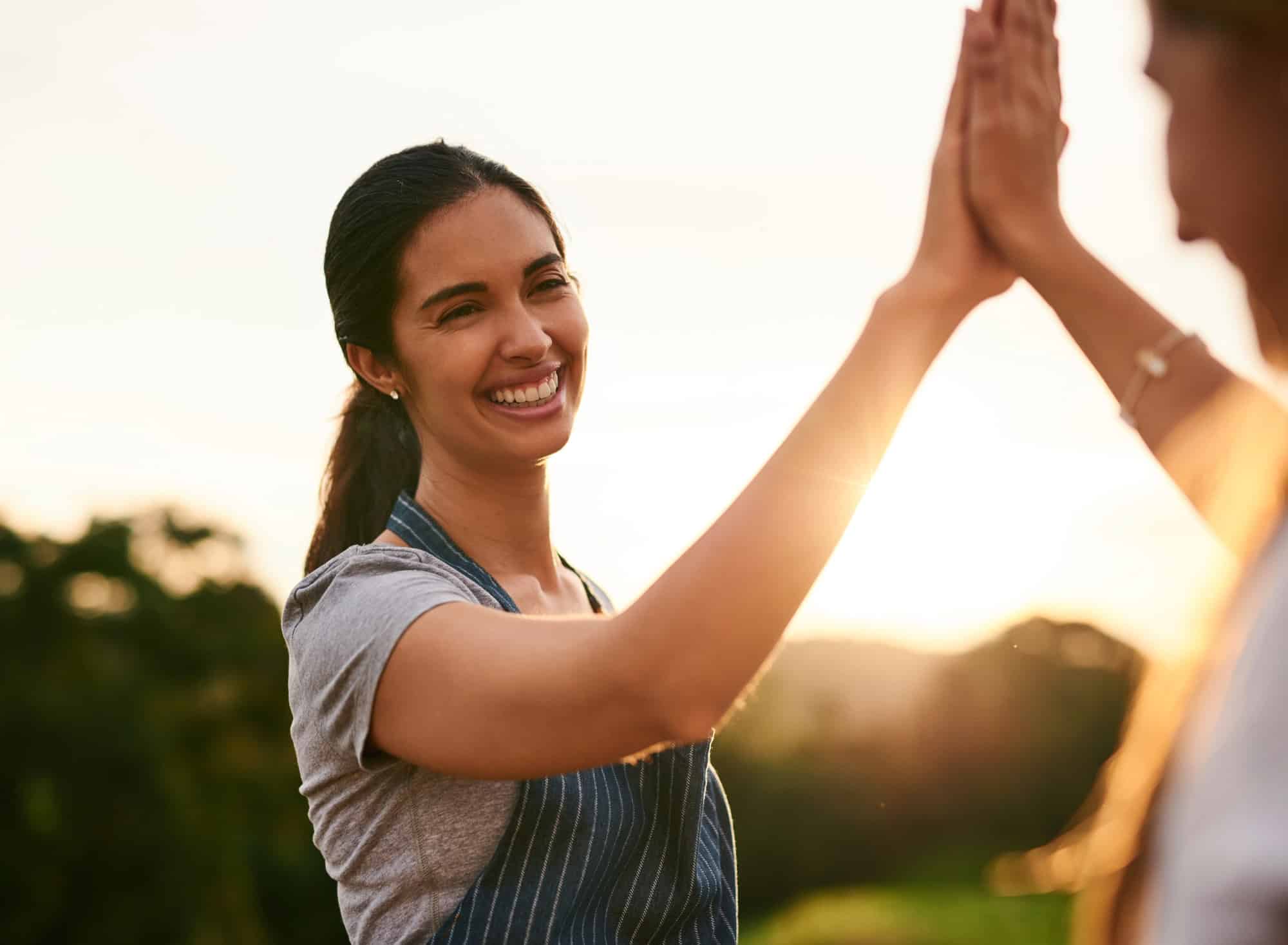 Two women sharing a high-five outdoors, symbolizing trust and partnership in healing