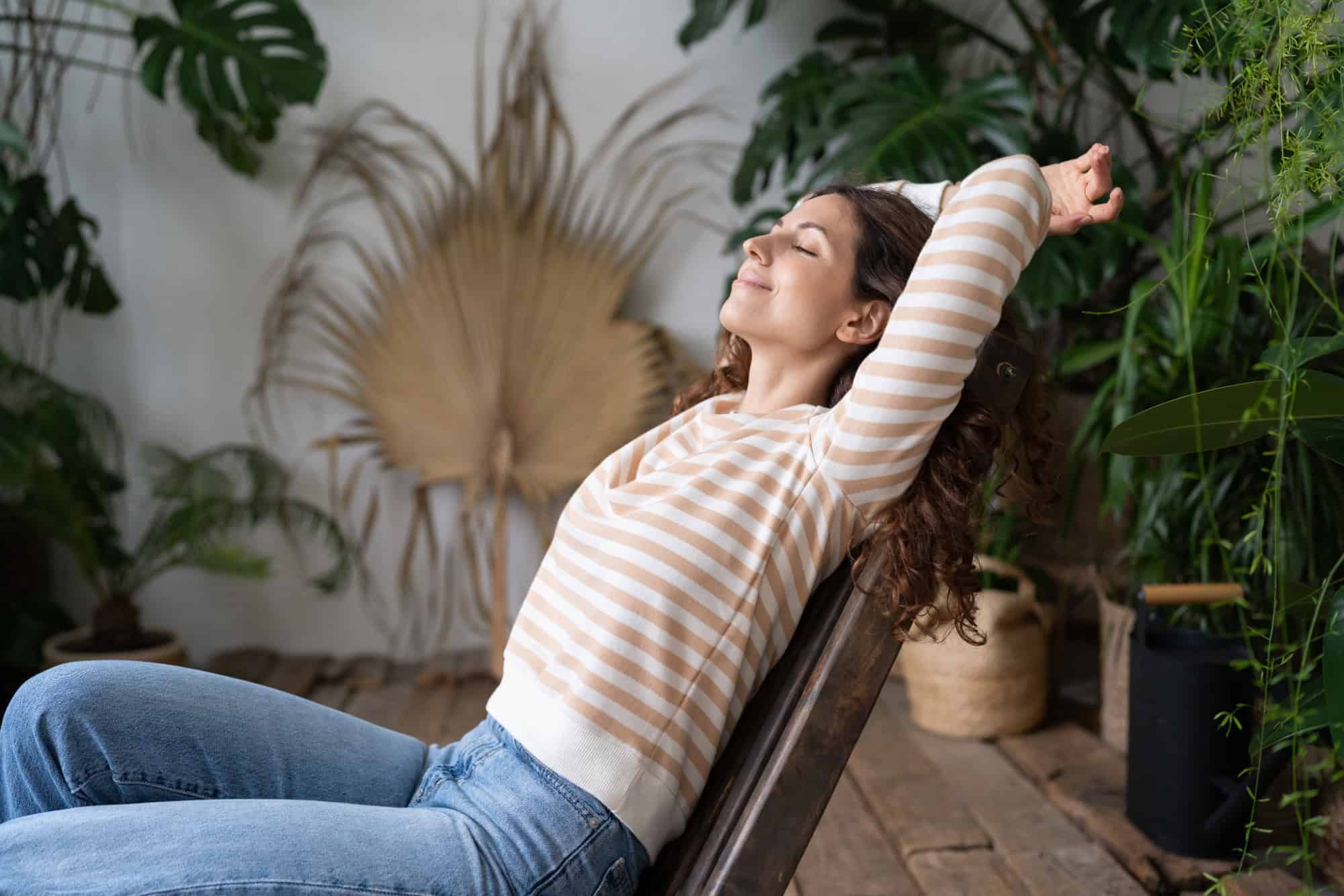 Relaxed woman stretching and smiling in a serene indoor space, reflecting HueLight’s approach to stress relief and wellbeing.