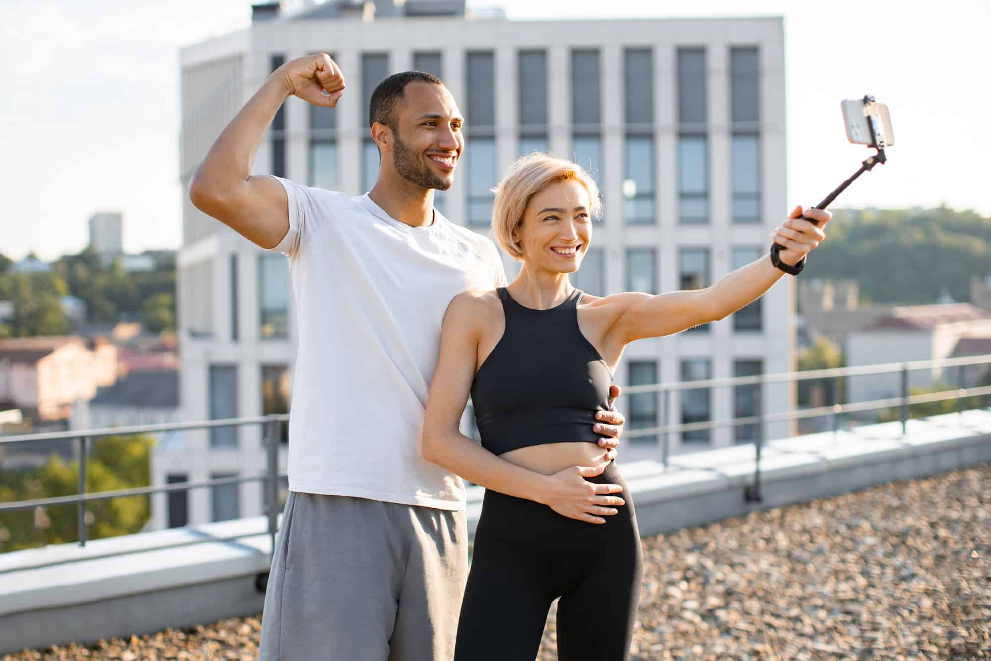 Fit couple taking a rooftop selfie after workout, smiling and energized, symbolizing active lifestyle and shared wellness journey.